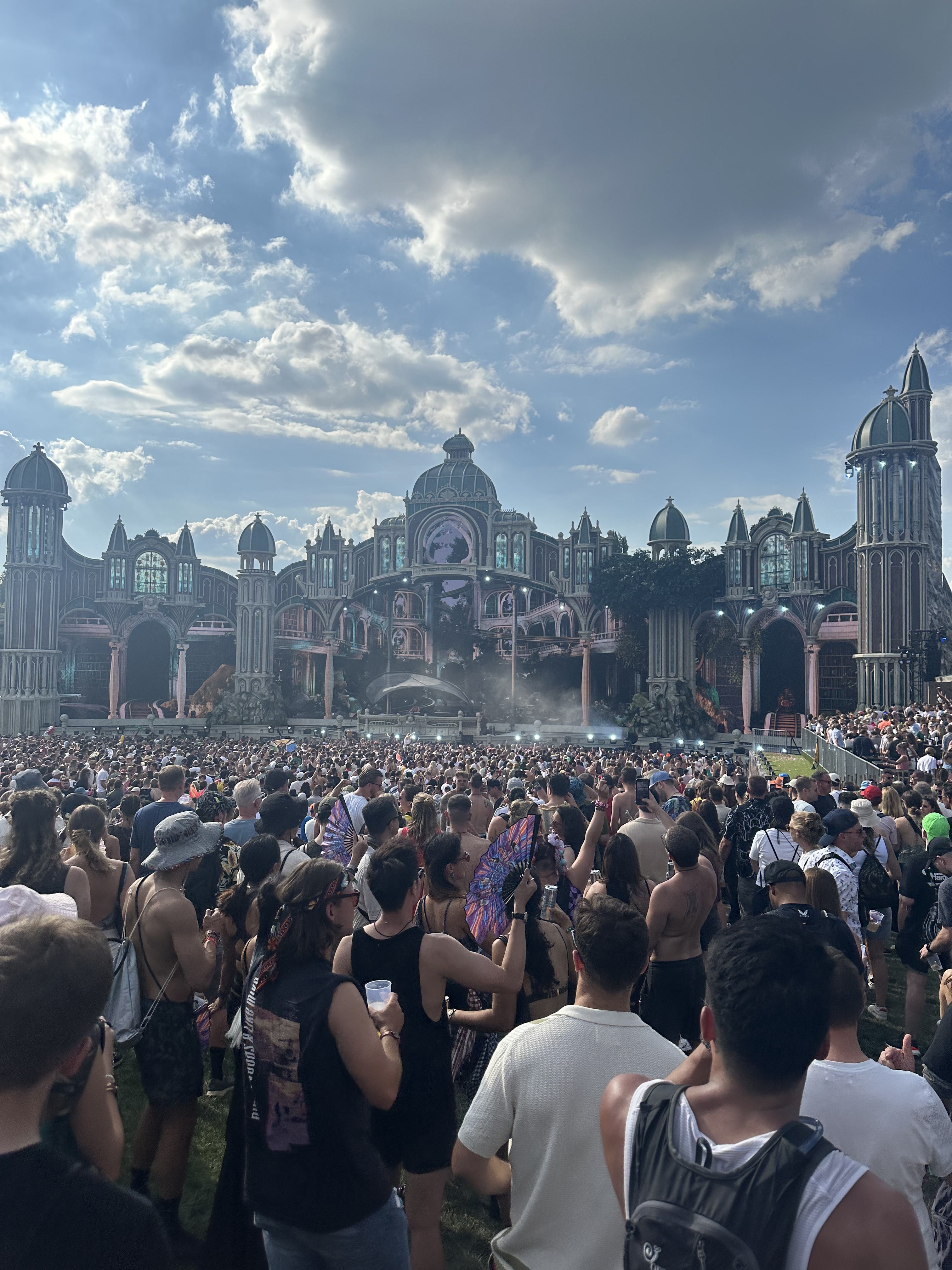 A festival crowd facing an ornate main stage beneath a bright sky